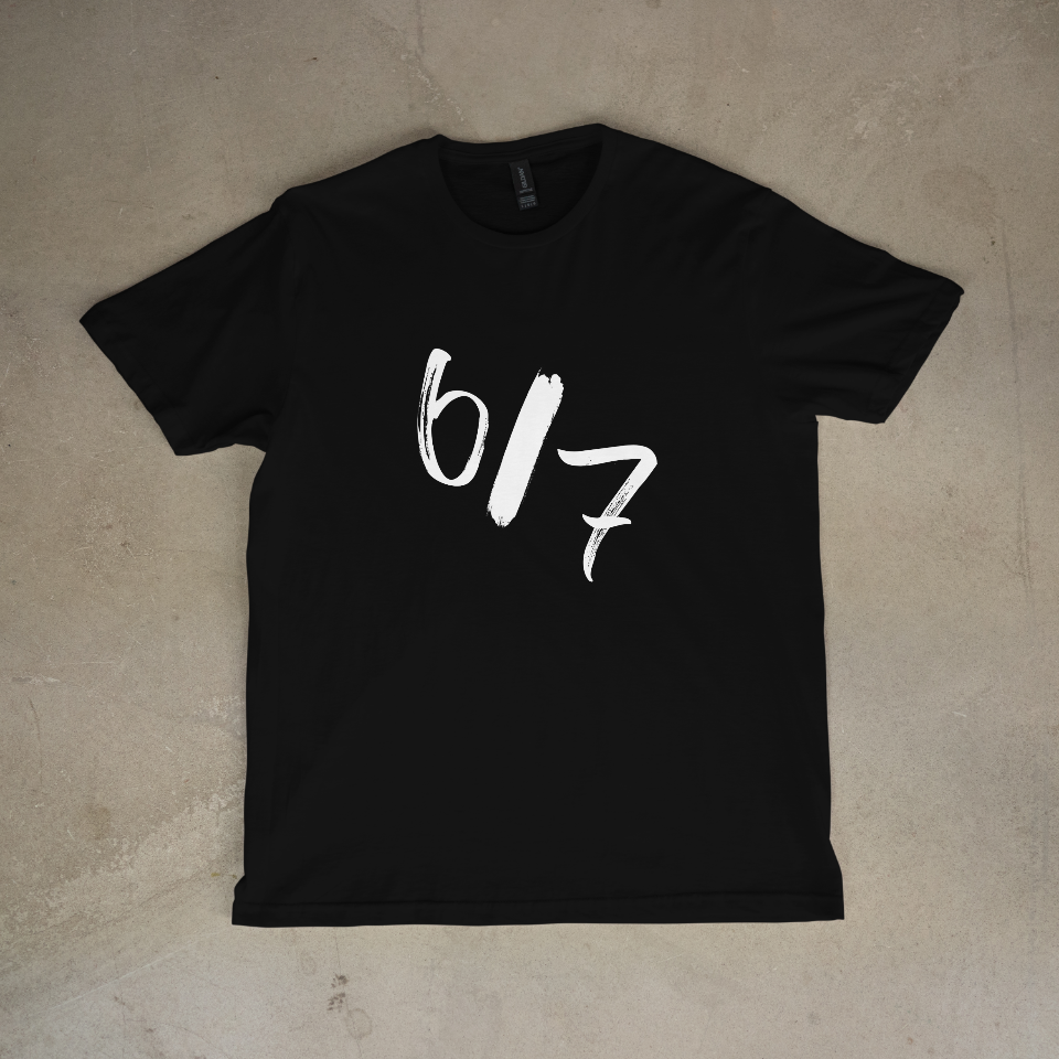 Black t-shirt with white text '6/7' on a beige surface