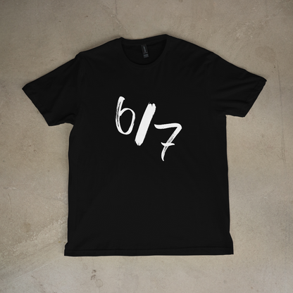 Black t-shirt with white text '6/7' on a beige surface