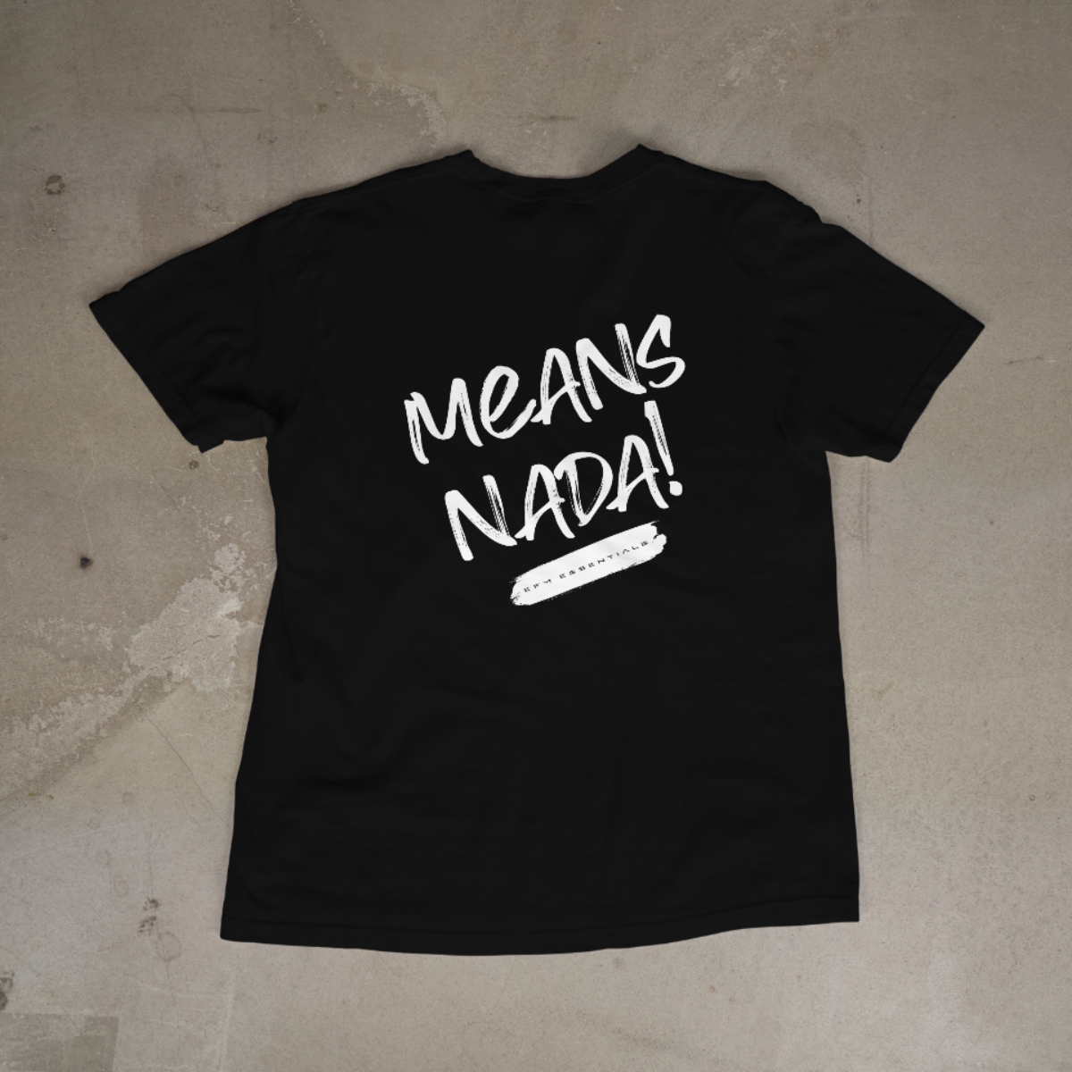 Black t-shirt with white text 'MEANS NADA!' on a concrete floor.