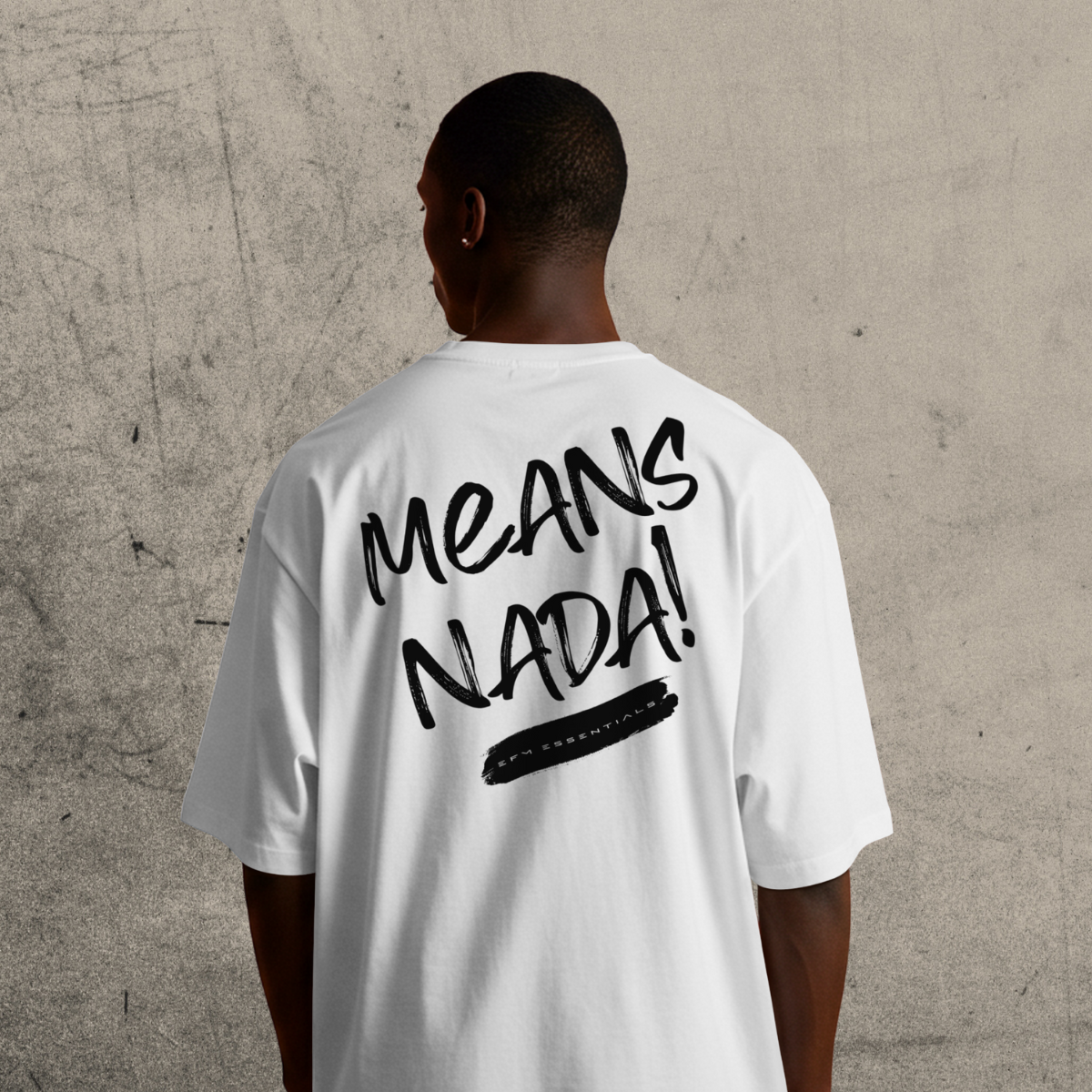 Person wearing a white t-shirt with 'MEANS NADA!' printed on the back against a textured wall.