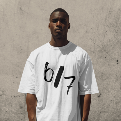 Man wearing a white t-shirt with '617' printed on it against a concrete wall.