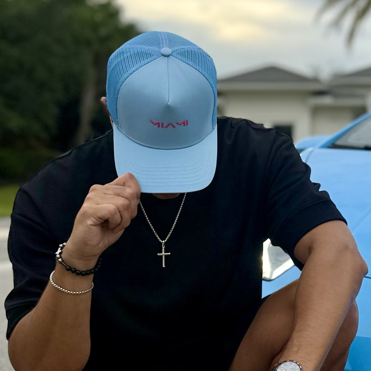 Person wearing a blue cap with 'Miami' text, sitting outdoors.