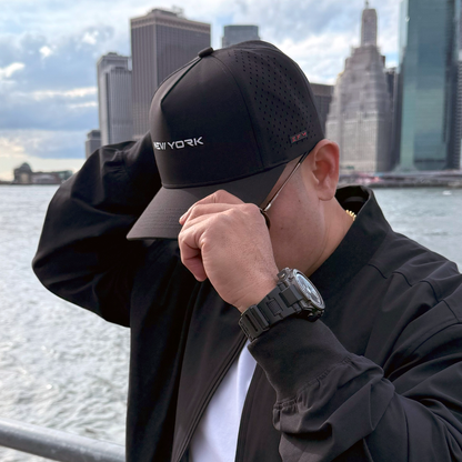 Person wearing a black 'New York' cap with a city skyline in the background